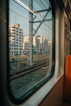View from the window of a moving train passing through a modern urban city landscape.