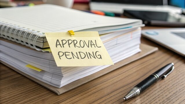 Notebook and Sticky Note with Approval Pending on Wooden Desk