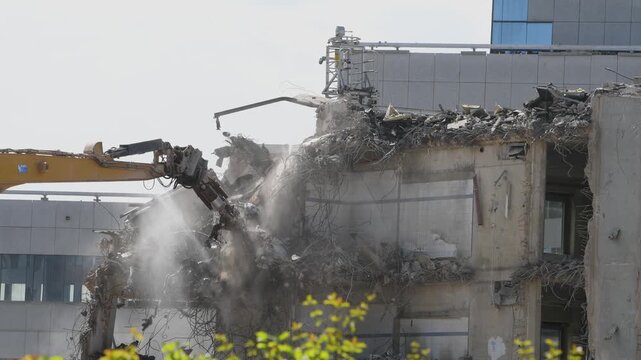 Construction site, demolition of reinforced concrete structure, gutting and renovation, hydraulic hammer dismantles building, caterpillar excavator machine