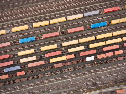 Santo Stefano di Magra, Italy - 18 April 2026: Aerial view of the Retroporto merci freight terminal with colorful cargo containers on multiple railway tracks.