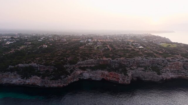 Calo des moro coastline is slowly revealing itself as the morning mist dissipates over the mediterranean sea