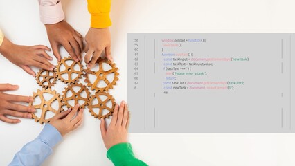 Obraz premium A close-up of diverse hands working together with wooden gears and coding elements, showcasing collaboration and innovation in a business or technology environment. Raster