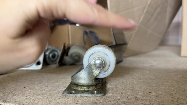 Hand spinning small caster wheel attached to furniture base to check movement