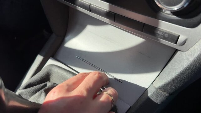 A hand opens a central console storage compartment in a car