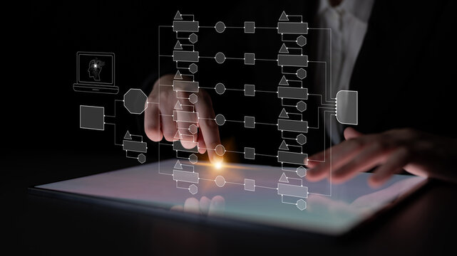 Business Professional Using Digital Tablet with Graphic Interface and Flowchart Concepts for Modern Analysis and Technology Solutions in Dark Setting Quark.