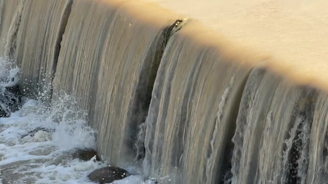 Waterfall flowing over concrete dam wall