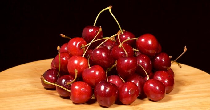 Close-up footage of napoleon cherries on a wooden tray against a black background.