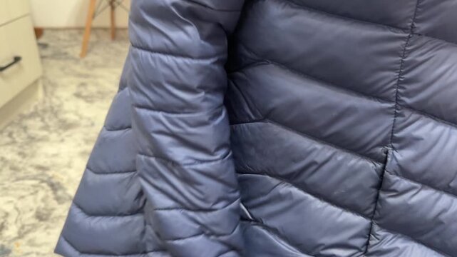 A person rubs the sleeve of a down jacket against the body of the jacket