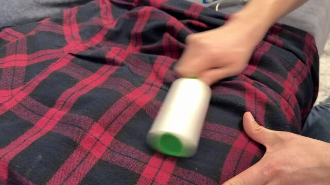 Hand using lint roller on plaid fabric clothing