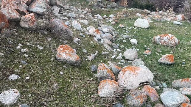 Large rocks rolling down grassy mountain slope among scattered stones and boulders, natural rockfall movement in rugged landscape, geological motion and erosion in wild outdoor terrain