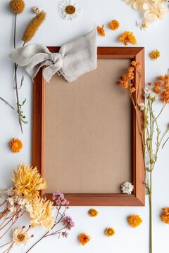 Wooden frame surrounded by dried flowers on white surface