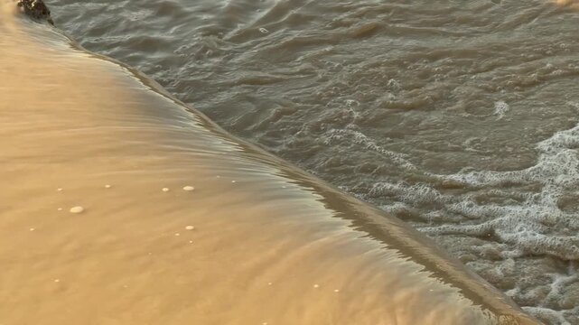 Golden sunset light reflecting on water flowing over dam edge