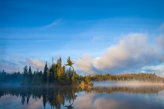 Island and shoreline with fog at dawn on a calm northern Minnesota lake during autumn