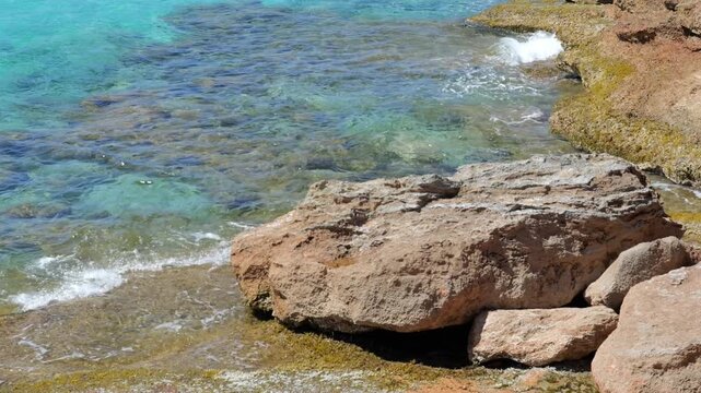 clear turquoise water near Porto Cristo, Mallorca, gently flowing over shallow rocks and a foreground stone. Ideal for travel, nature or background footage with calm and clean visual mood. 4K UHD (384