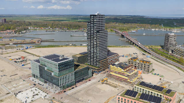 Amsterdam, Netherlands - 14 April 2026: Aerial view of Sluisbuurt district featuring modern skyscrapers, construction sites, and the Enneus Heerma Bridge over the water under a blue sky.