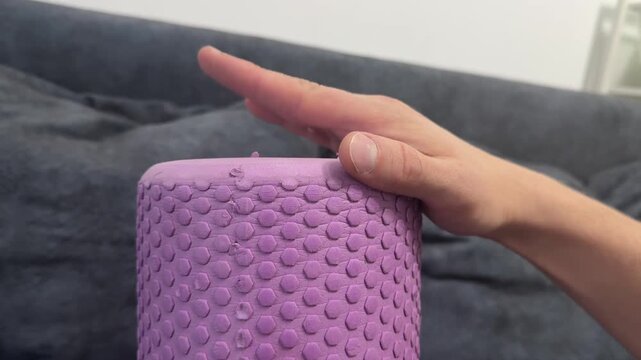 Fingers rhythmically tapping on a pink textured foam roller