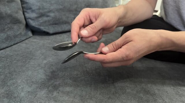 Hand tapping a spoon against a spoon