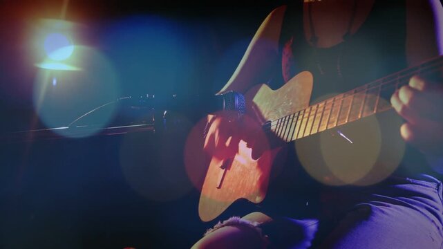 Camera pan revealing female teen musician playing guitar animated bokeh accenting hands for music