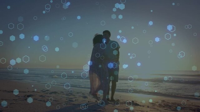 Couple holding hands on sand pivoting after hand pull, walking for travel under hex-bokeh-overlay