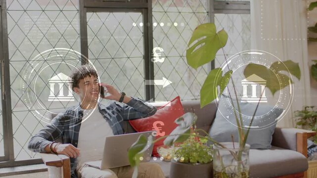 Man on sofa answering banking call by phone using laptop, animated bank icons &euro;&yen;&pound;$ overlaying frame