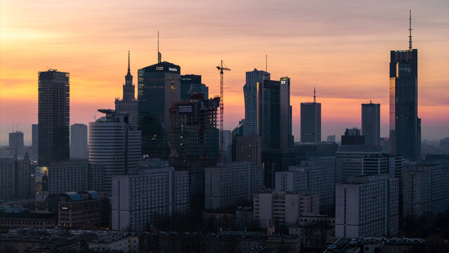 Warsaw, Poland - 06 March 2026: Aerial view of Warsaw city skyline with modern skyscrapers and construction cranes under a vibrant sunset sky.