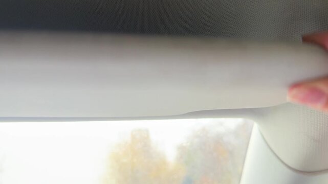 Hand raising and lowering sun visor inside car interior