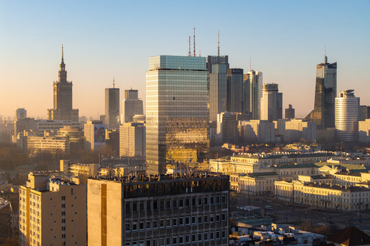 Warsaw, Poland - 07 March 2026: Aerial view of the city skyline featuring the Palace of Culture and Science and modern skyscrapers during golden hour with warm light reflecting off glass facades.