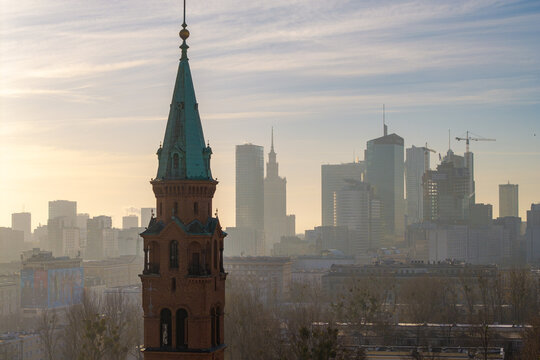 Warsaw, Poland - 05 March 2026: Aerial view of the historic St. Augustine's Church spire with the modern city skyline and skyscrapers in the morning haze.