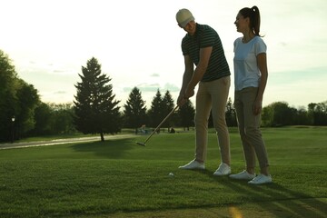 Obraz premium Happy couple playing golf on green course, space for text