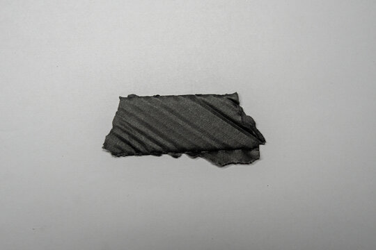 A piece of black tape on a white paper background, illustrating the concept of repair and binding. This image can be used for marketing materials related to DIY, crafts or repairs.