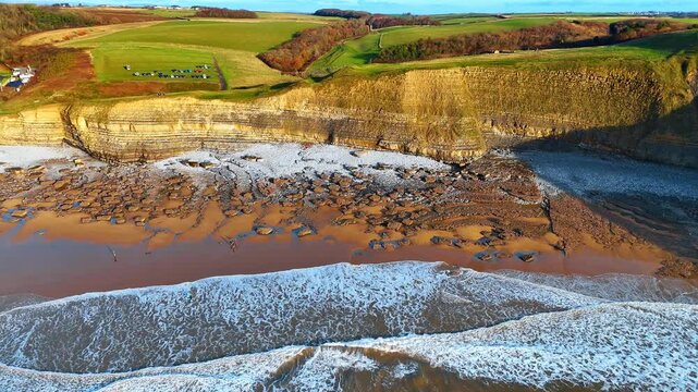 Top down view of rocky shoreline and limestone cliff layers. High angle aerial perspective of the geological formations and rocky beach at Southerndown, South Wales.