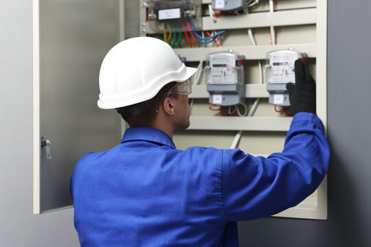 Electrician checking fuse box with electrical meters indoors