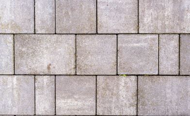 Fototapeta premium A close-up view of a textured concrete pavement featuring a regular pattern of rectangular stones. The image showcases wear and minor imperfections, suitable for architectural and landscaping project