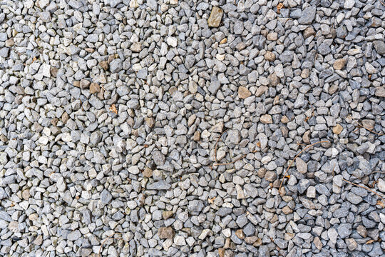 Textured gravel surface featuring small stones in various shades of gray, creating a natural aggregate backdrop. Ideal for construction projects, landscaping, or design applications.