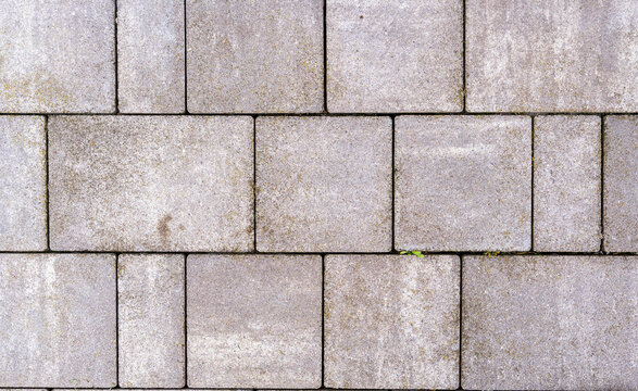 A close-up view of a textured concrete pavement featuring a regular pattern of rectangular stones. The image showcases wear and minor imperfections, suitable for architectural and landscaping project