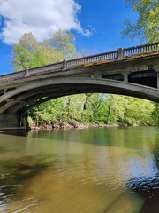 Obraz premium Stone bridge crossing calm river under blue spring sky