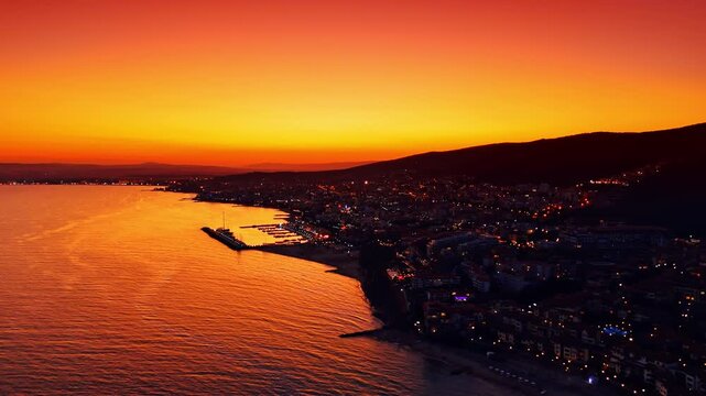 Flight over the waterscape along the shore with dense urban landscape. Resort coast of Bulgaria at subset time.