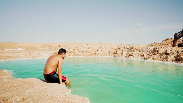 young man floating in bright blue salt pool wearing bathing suit in Siwa Oasis, Egypt