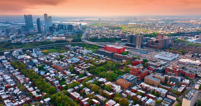 Pink sky over the vast green cityscape of Jersey City, New Jersey, USA. Footage over the panorama at sunset.