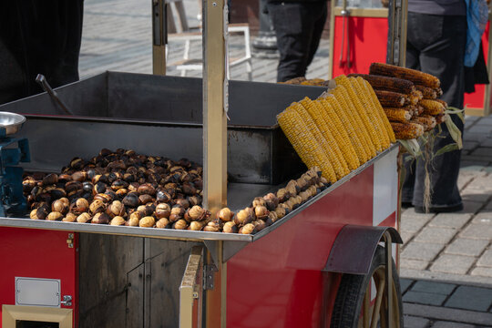 Street food cart with roasted chestnuts and grilled corn in Istanbul outdoor market with metal tray, cooking setup. Street food, local cuisine, tourism marketing, urban food culture, travel content