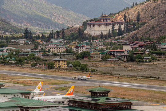 PARO, BHUTAN - MAY 7, 2025: Aerial view of airplanes at Paro International Airport under Rinpung Dzong, Buddhist monastery and fortress, Bhutan