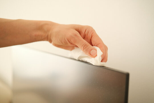 Woman hand cleaning computer monitor with wet cleaning wipe