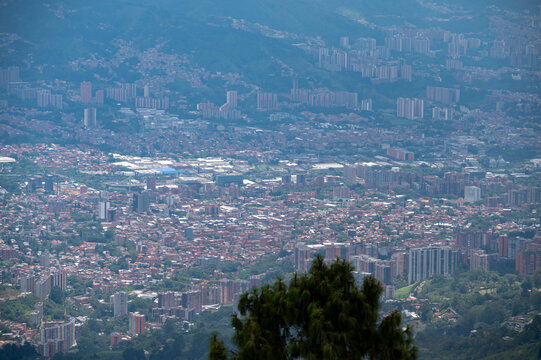 A crisp, mid-range shot of modern residential high-rise buildings in Envigado, Antioquia. The architecture features the region's signature red-brick facades contrasted with lush tropical greenery and 