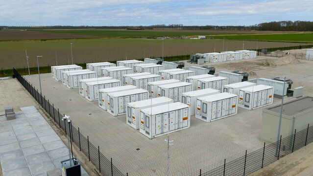 Dronten, Netherlands - 4 April 2026: Aerial view of the Olsterdwarspad battery storage facility with rows of white containers in a fenced area surrounded by flat agricultural fields.