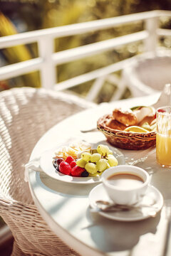 breakfast on terrace with coffee fruits and pastries, sunlight, cozy atmosphere, outdoor relaxation, summer morning