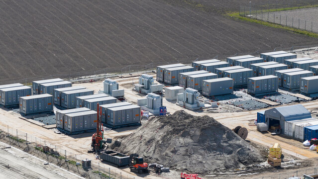 Espel, Netherlands - 04 April 2026: Aerial view of Hoogspanningsstation - Westermeerdijk with rows of grey battery storage containers, electrical transformers, and construction equipment.