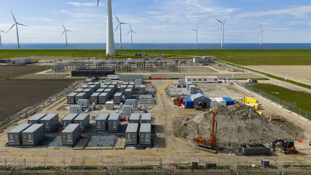 Espel, Netherlands - 04 April 2026: Aerial view of Hoogspanningsstation Westermeerdijk battery storage facility under construction with wind turbines and the sea in the background.