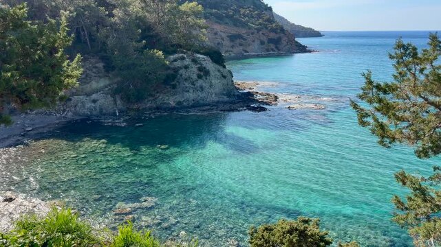 Mediterranean lagoon in Cyprus Akamas with clear blue water and coastal cliffs, pine trees, ideal for tourism and eco travel marketing. Natural landscape highlights relaxation and destination appeal. 