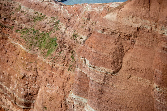 Erodierte Gesteinsschichten in roter und beiger Farbe mit sichtbaren geologischen Formationen und Verwitterungsspuren