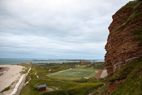 Felsk&uuml;ste mit Sportplatz und Strand auf Helgoland, Oberland, Schleswig-Holstein bei bew&ouml;lktem Himmel